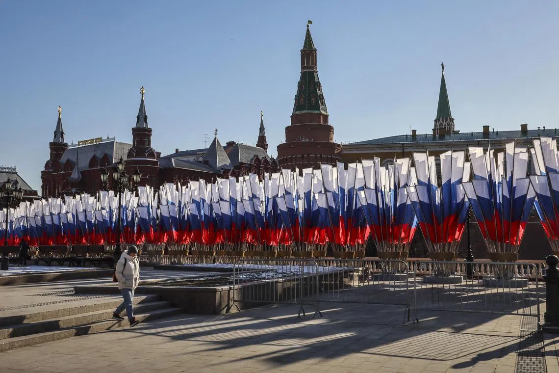 epa11923092 A woman walks next to Russian flags placed in front of the Moscow Kremlin on a clear sunny day in Moscow, Russia, 25 February 2025.  EPA-EFE/YURI KOCHETKOV
