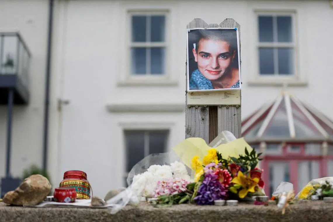 A picture of late singer Sinead O'Connor, who died at the age of 56, known for her chart-topping hit \"Nothing Compares 2 U\", is placed around floral tributes outside her former Irish home, in the seaside town of Bray in County Wicklow, Ireland, July 27, 2023. REUTERS/Damien Storan/File Photo