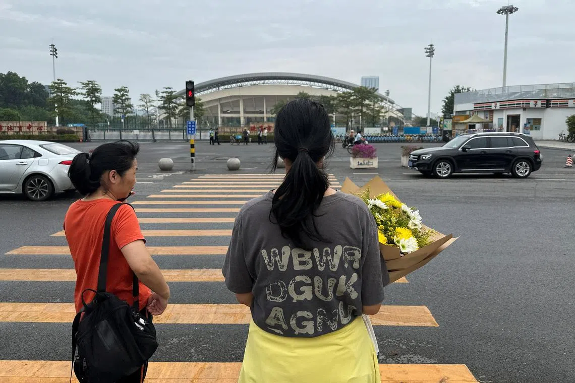 A woman holds a bouquet of flowers as she heads towards the sports centre where a deadly car attack took place, to pay tribute, in Zhuhai, Guangdong province, China November 13, 2024. REUTERS/Tingshu Wang