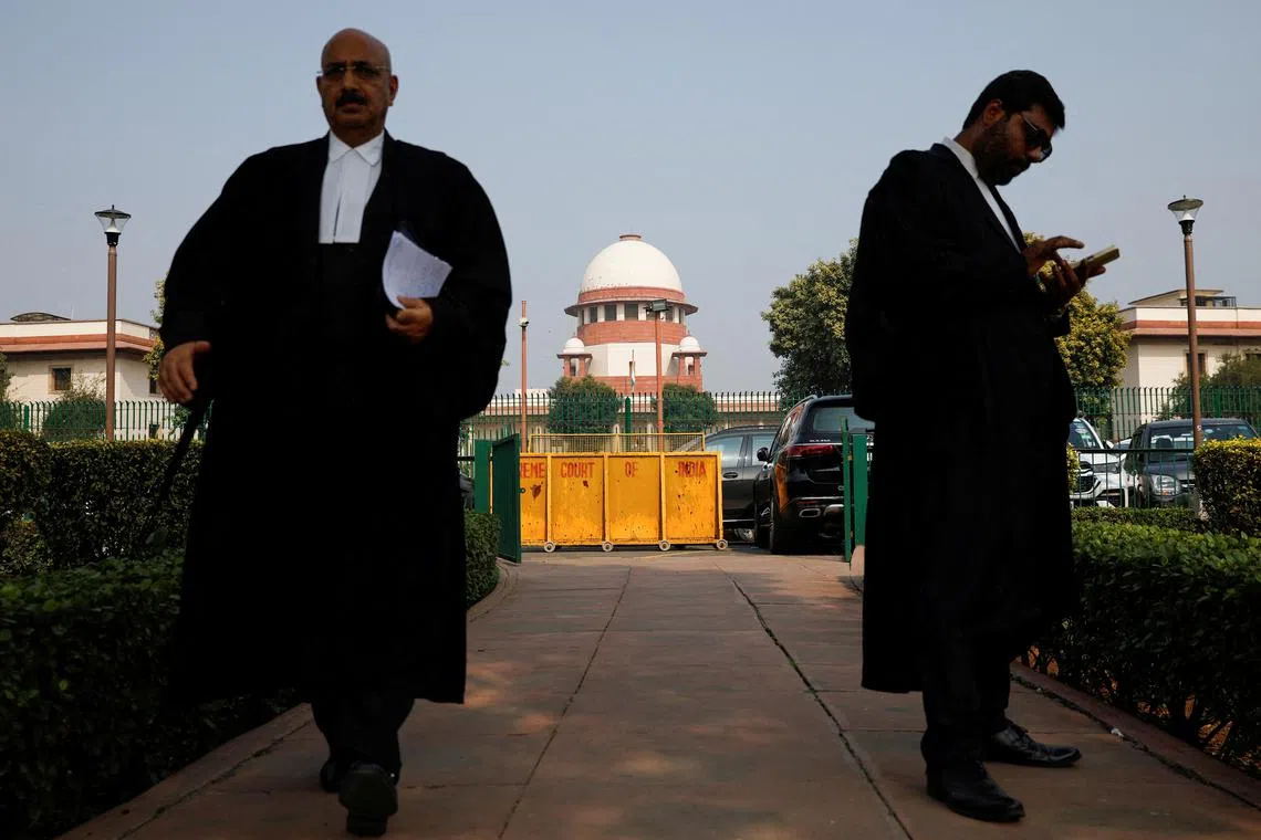 FILE PHOTO: A lawyer looks into his mobile phone as another walks past, in front of India's Supreme Court in New Delhi, December 11, 2023. REUTERS/Adnan Abidi/File Photo