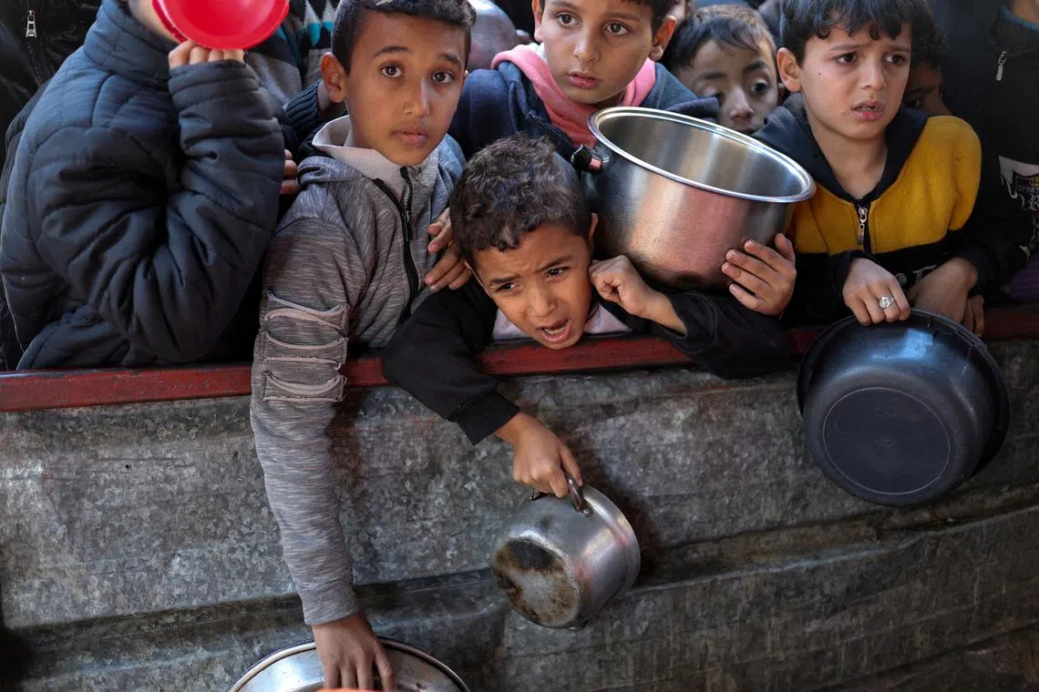FILE PHOTO: Palestinian children wait to receive food cooked by a charity kitchen amid shortages of food supplies, as the ongoing conflict between Israel and the Palestinian Islamist group Hamas continues, in Rafah, in the southern Gaza Strip, February 5, 2024. REUTERS/Ibraheem Abu Mustafa/File Photo