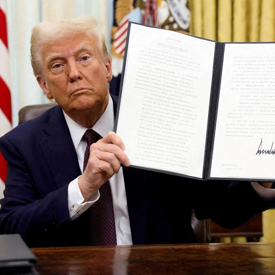 US President Donald Trump holds a signed executive order on cryptocurrencies, in the Oval Office of the White House.