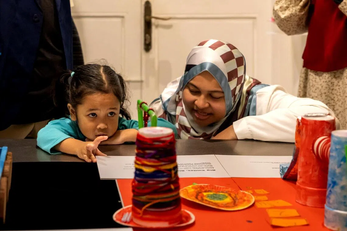 A child from Iyad Perdaus Hougang points to Big Smiles, Big Play!, an artwork created by children from her pre-school.