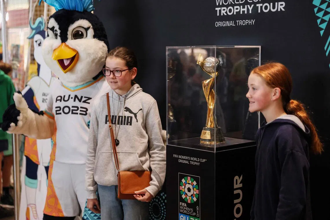 People pose with the trophy for the Australia and New Zealand 2023 FIFA Women's World Cup at a shopping mall in Auckland on June 5, 2023. (Photo by MICHAEL BRADLEY / AFP)