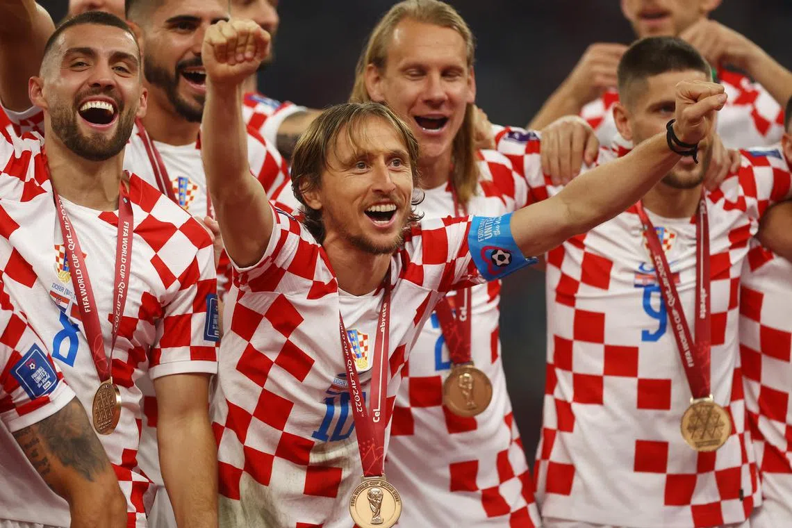 Croatia's Luka Modric and teammates celebrate with their medals on stage as they finish in third place.