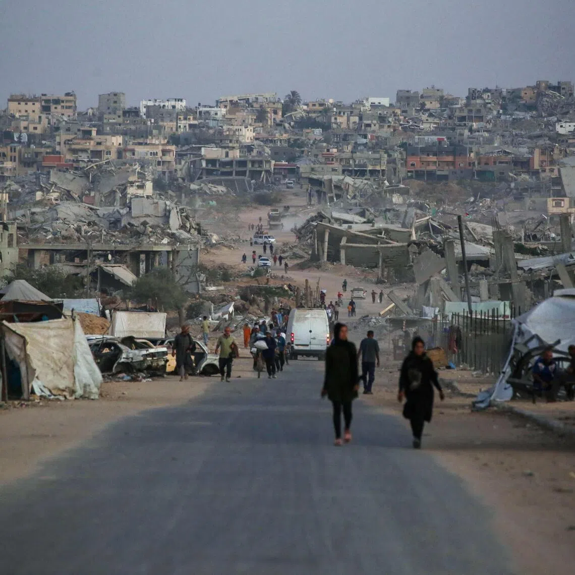 Palestinians walking along a road past destroyed buildings in Khan Younis, in the southern Gaza Strip on Oct 25.