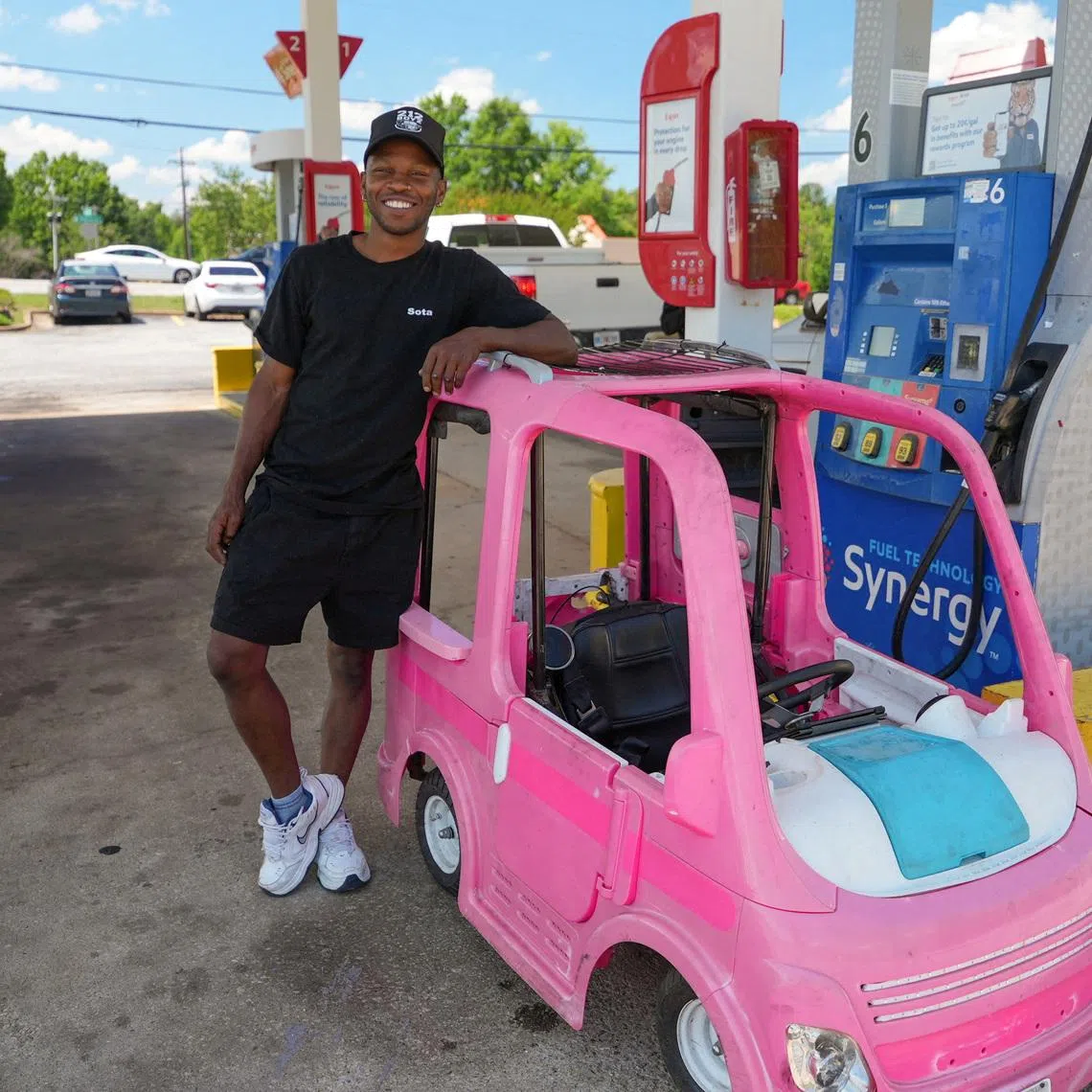 Mr Mali Hightower poses with what he describes as a self-created gas saver, a pink Power Wheels Barbie Dream Camper that he now uses to run errands.