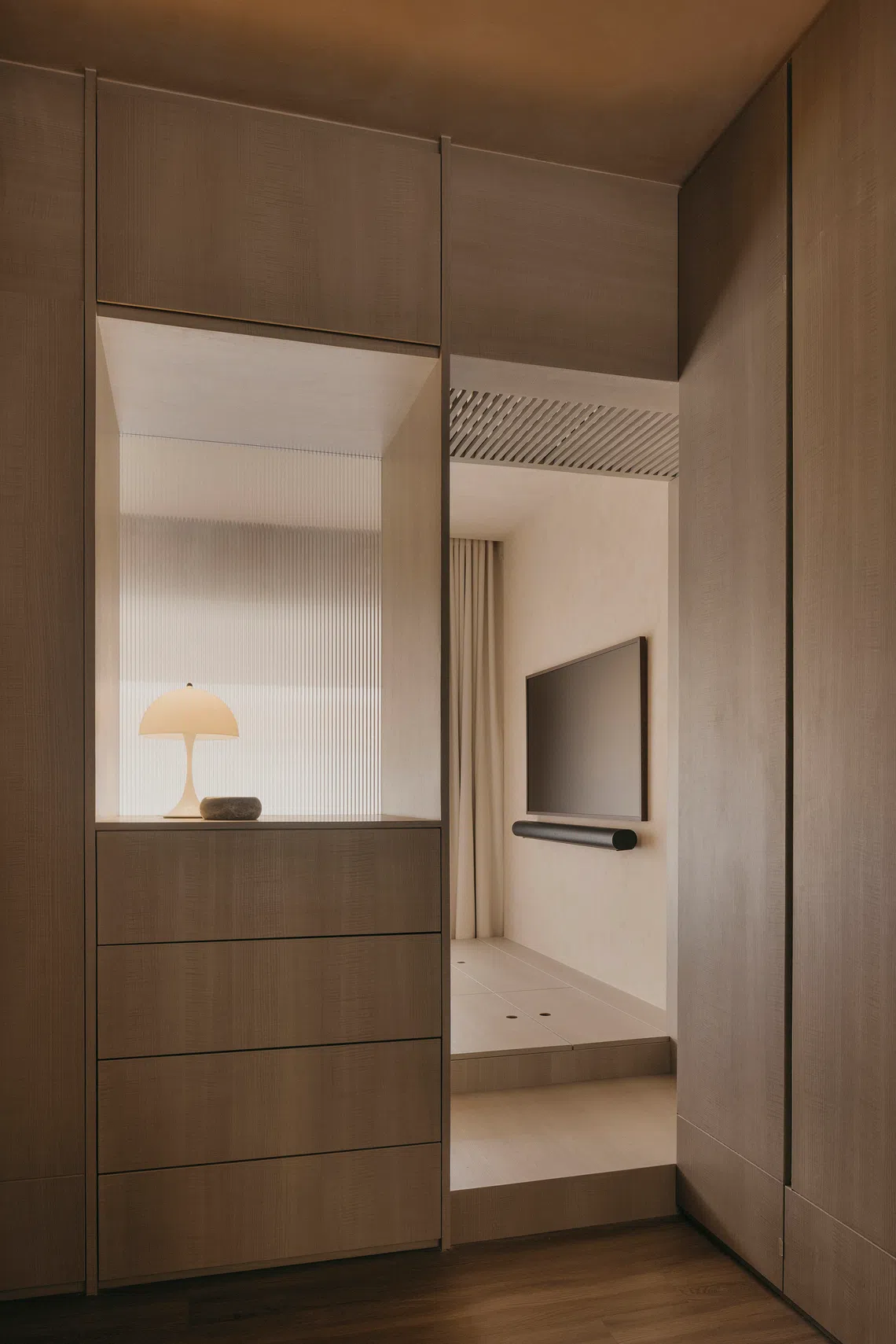 Fluted glass provides privacy for the sleeping zone, where there is a TV facing the bed.