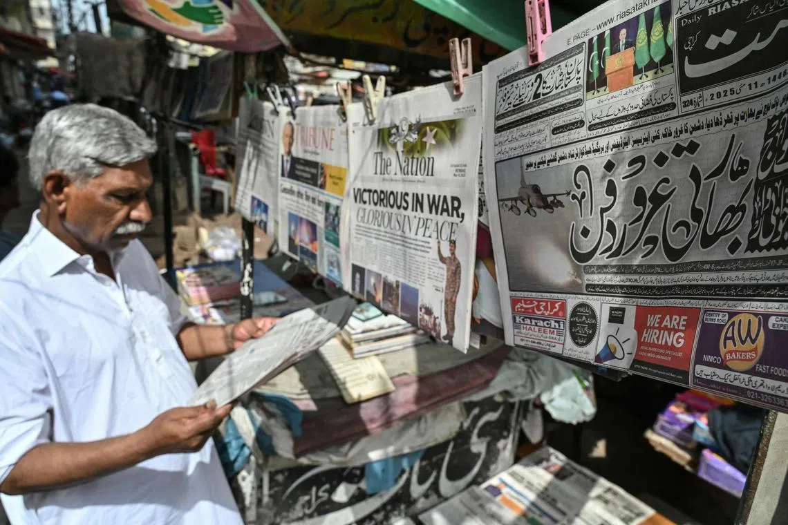 A resident reads a morning English newspaper at a roadside stall in Karachi on May 11.