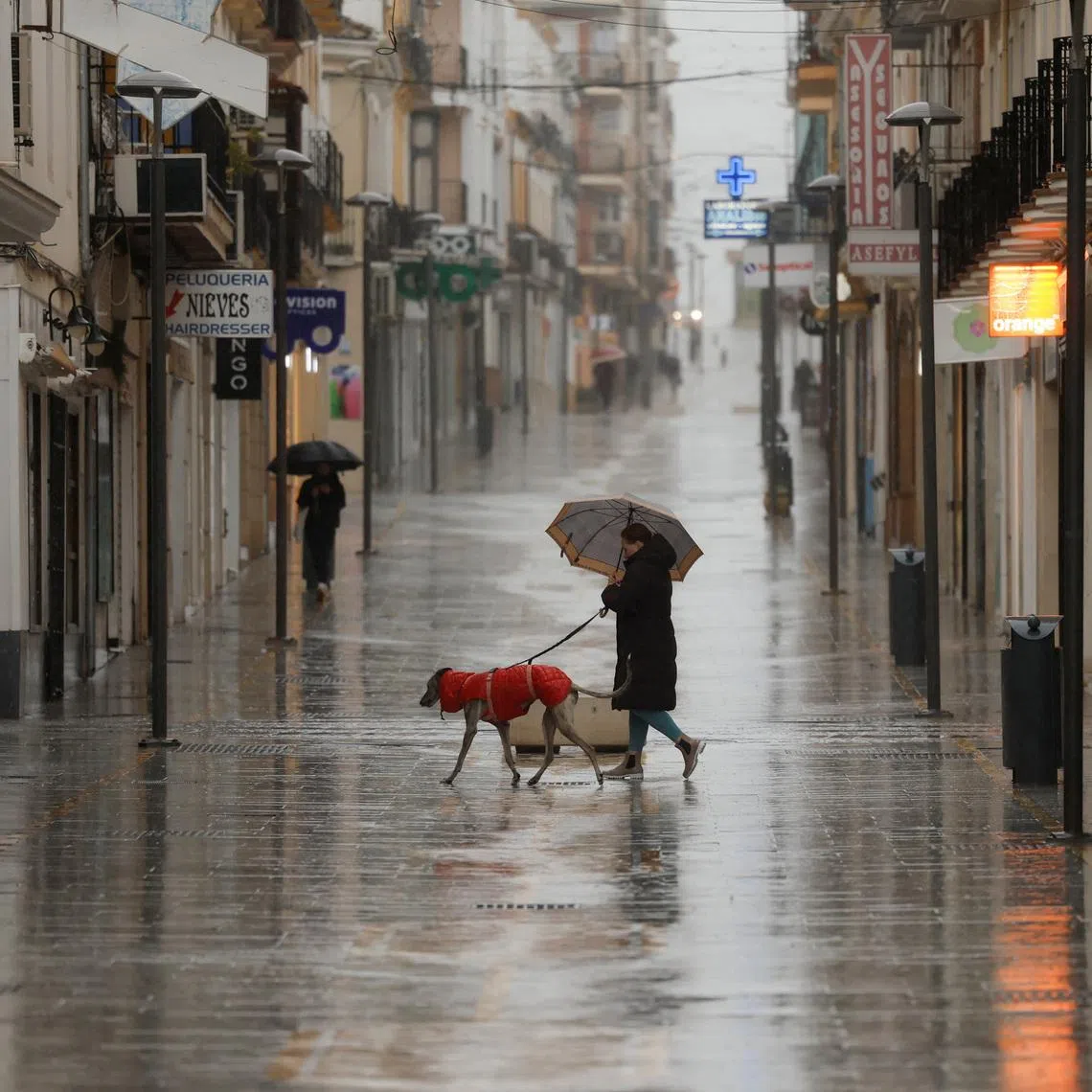 People walk in a shopping area amid rain as storm Leonardo hits parts of Spain, in Ronda, Spain, February 4, 2026. REUTERS/Jon Nazca