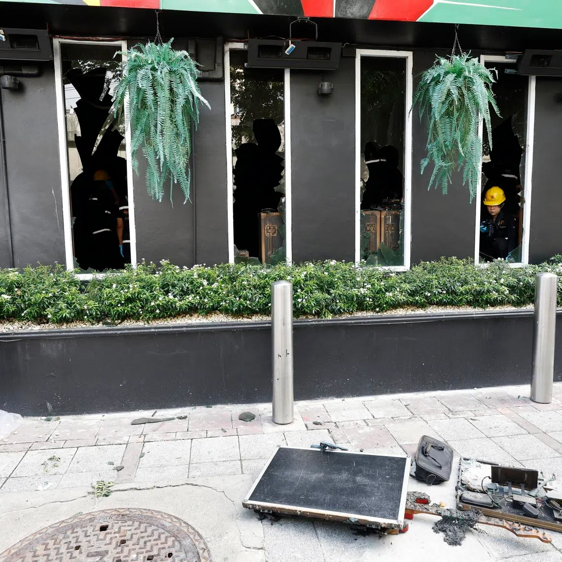 A charred guitar lies amid the damage as a Thai forensic police officer examines broken windows at the scene of the fire at Rong Beer Na Lat Phrao bar and restaurant.