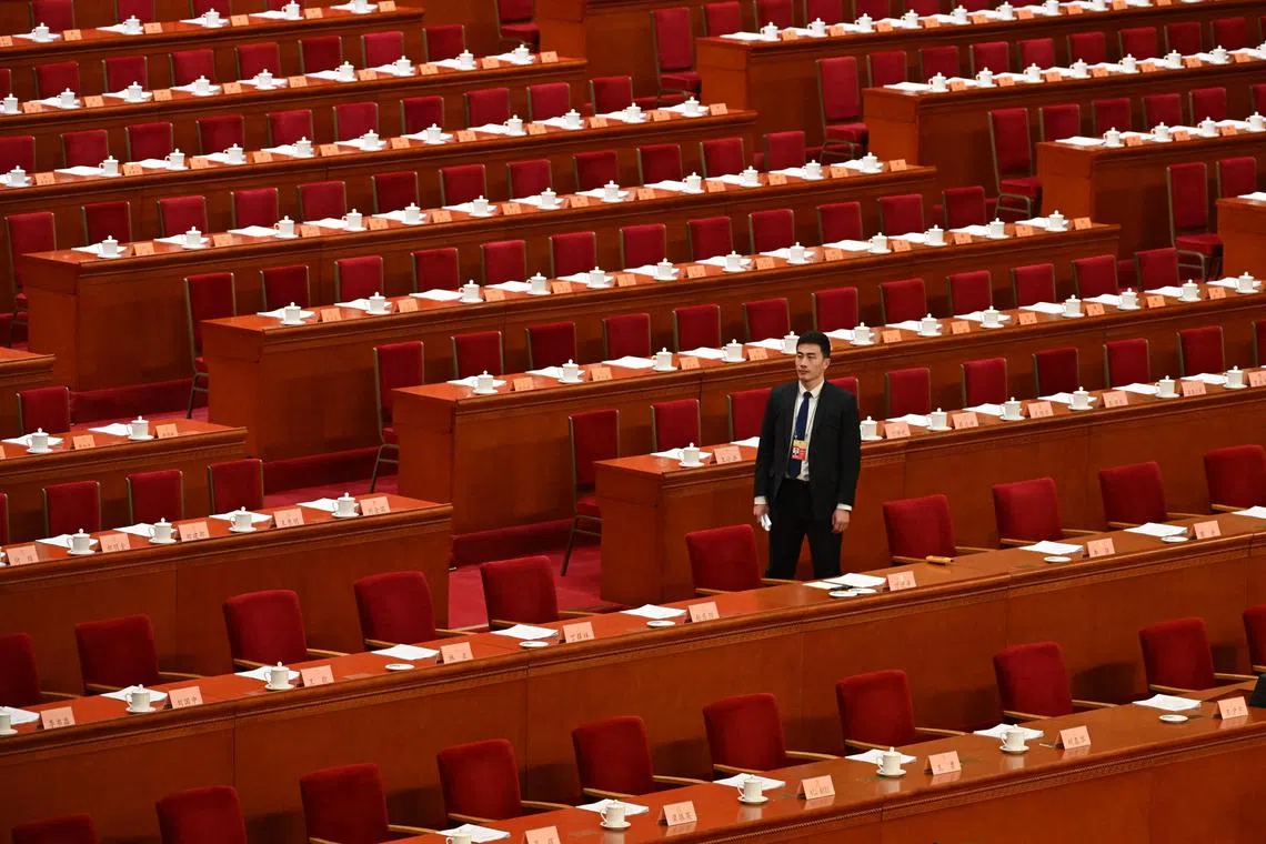 A security official walks past seats before the arrival of delegates for the opening ceremony of the Chinese People's Political Consultative Conference (CPPCC) at the Great Hall of the People in Beijing on March 4, 2024. (Photo by GREG BAKER / AFP)