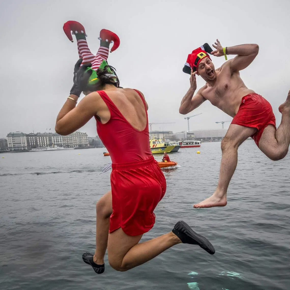 TOPSHOT - Disguised swimmers dive into Lake Geneva during the 87th "Coupe de Noel" (Christmas Cup) swimming race in Geneva on December 20, 2025. More than 4,200 participants took part in the traditional two-day event, a 120m-long swim off Geneva's banks into the 8.9 degrees Celsius water. (Photo by Fabrice COFFRINI / AFP)