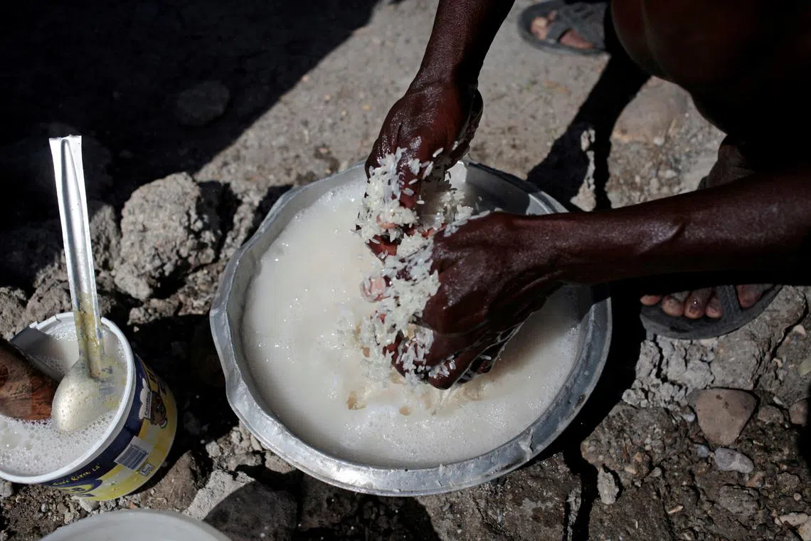 FILE PHOTO: A woman washes rice before cooking it next to a house destroyed by Hurricane Matthew in Jeremie, Haiti, November 3, 2016. REUTERS/Andres Martinez Casares/File Photo