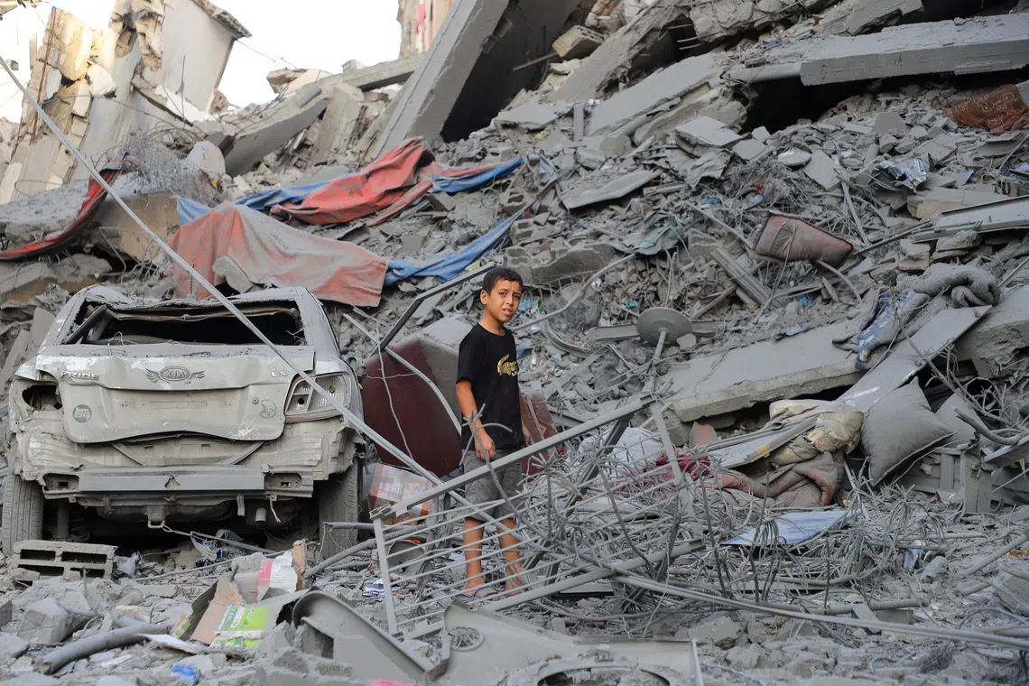 A Palestinian boy stands amidst the rubble as he inspect the site of Israeli strikes on houses at Shati (Beach) refugee camp, amid an Israeli military operation, in Gaza City, September 26, 2025. REUTERS/Ebrahim Hajjaj