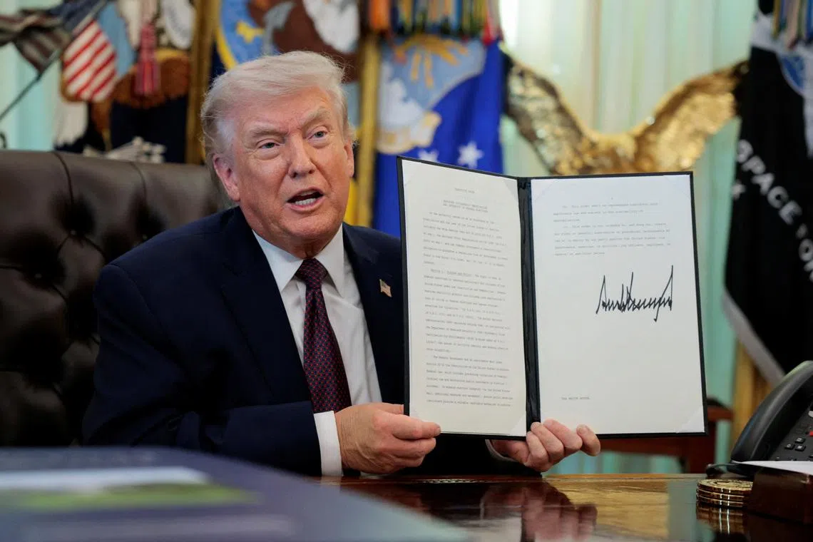 US President Donald Trump speaks as he shows a signed executive order on mail ballots, in the Oval Office of the White House.