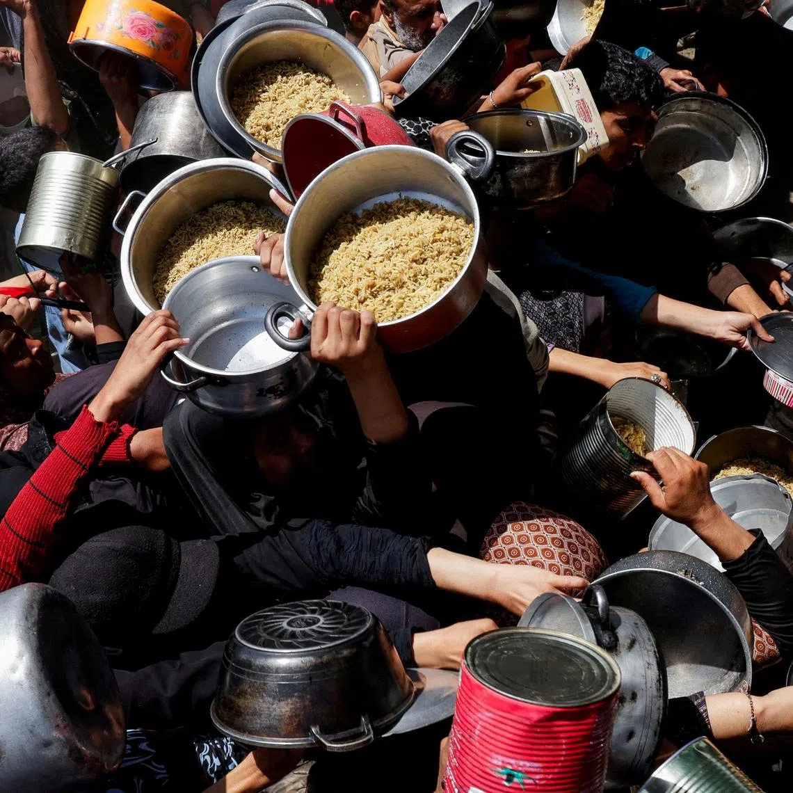 Palestinians gather as they receive food cooked by a charity kitchen, in Khan Younis, southern Gaza Strip, April 29, 2025. REUTERS/Hatem Khaled