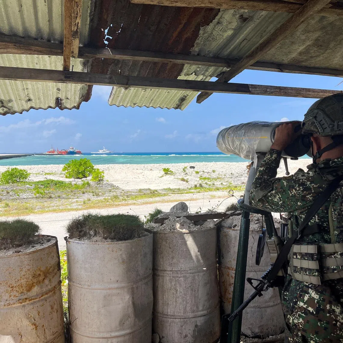 A Philippine soldier peers through an observation telescope from a viewing deck in Philippine-occupied Thitu Island in the disputed South China Sea, February 21, 2026. Picture taken with a mobile phone. REUTERS/Karen Lema