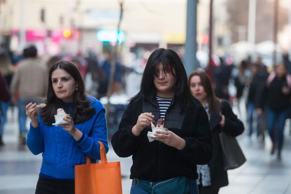People eat ice cream during a heat wave in Santiago on August 2, 2023. South American countries, such as Chile and Argentina, set heat records in the middle of the southern winter due to a combination of the El Niño phenomenon and climate change, which also impacts the northern hemisphere with record high temperatures, but in the summer. (Photo by Pablo Vera / AFP)