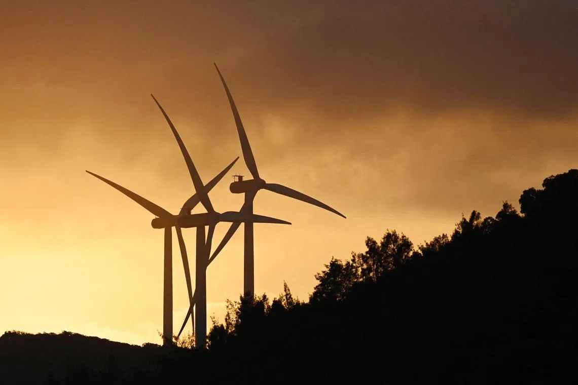 Wind turbines are seen at sunset on Pingtan Island, in China's southeast Fujian province on January 16, 2024. (Photo by GREG BAKER / AFP)