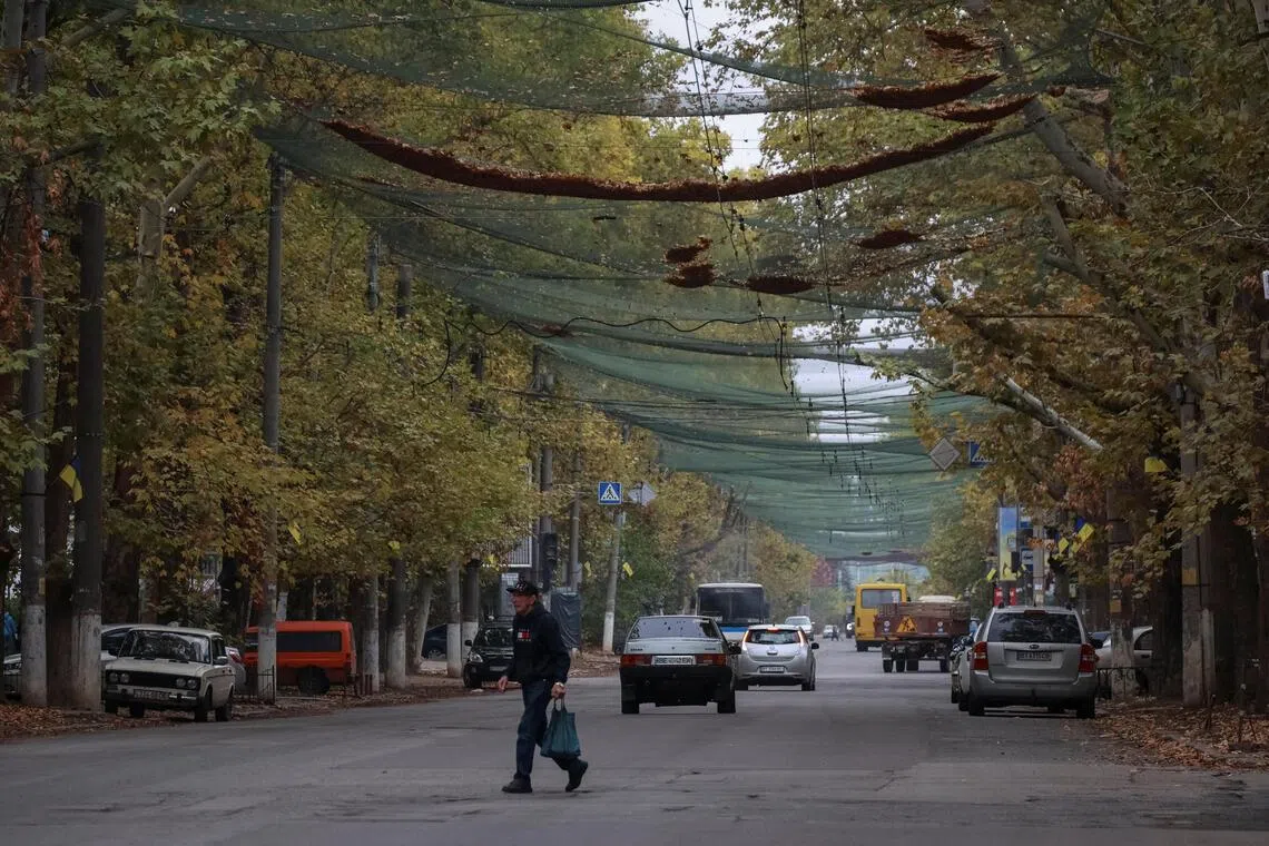 A resident crossing a street in the front-line city of Kherson, Ukraine, on Oct 2, 2025. The street is covered with an anti-drone net, to prevent grenade attacks using drones.