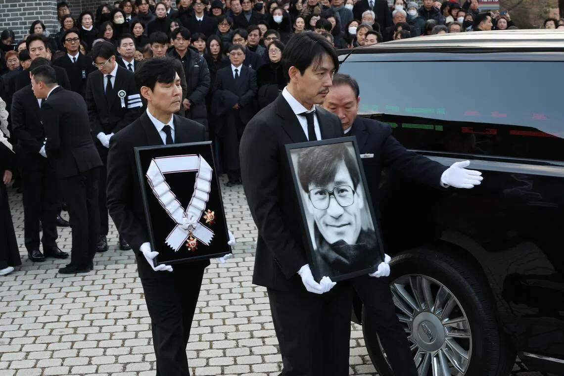 epa12637255 Actors Chung Woo-sung (R) and Lee Jung-jae (L) carry the portrait of late film star Ahn Sung-ki and the Geumgwan Order of Cultural Merit posthumously conferred on him by the government, respectively, during a funeral for him at Myeongdong Cathedral in Seoul, South Korea, 09 January 2026. Ahn, one of the country's most beloved actors, died at age 74 on 05 January, after collapsing while choking on food at his home on 30 December 2025.  EPA/YONHAP SOUTH KOREA OUT