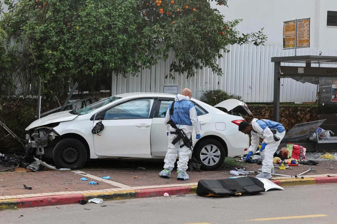 Israeli police forensics personnel inspect a damaged car following a suspected ramming attack in the central town of Raanana.