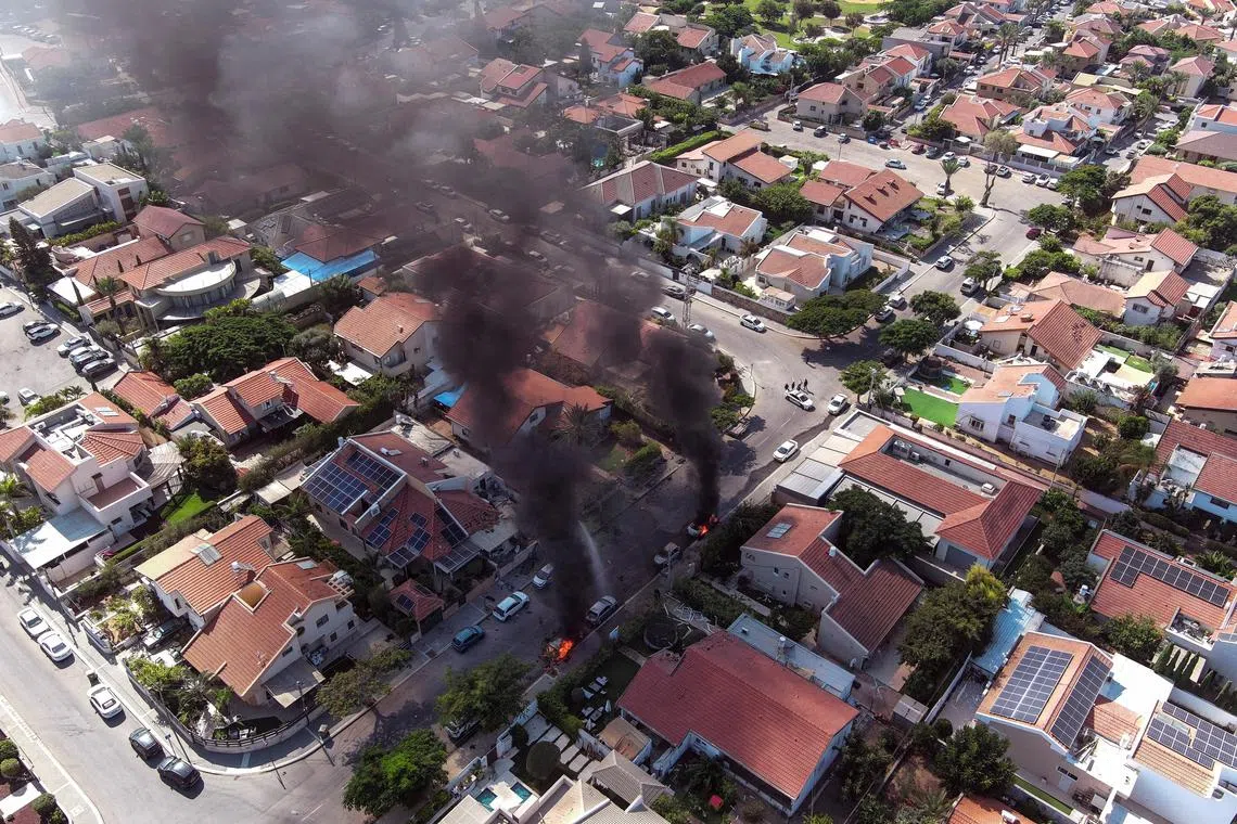 Vehicles on fire as rockets are launched from the Gaza Strip, in Ashkelon, Israel, on Oct 7.