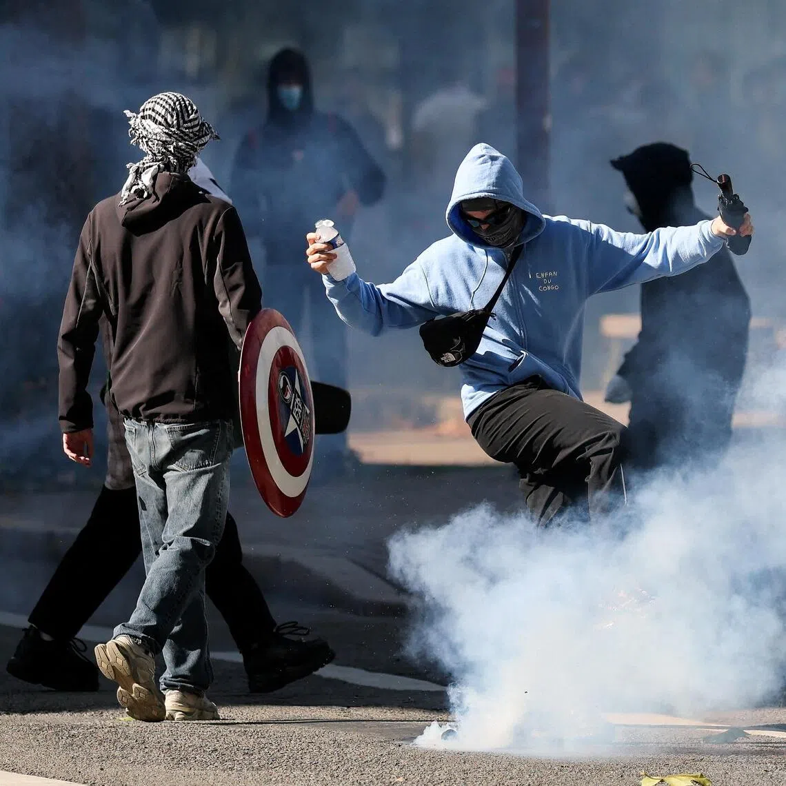 A person kicking a tear gas canister in Nantes, France, on Oct 8, as French high school and university students demonstrate for better school conditions.