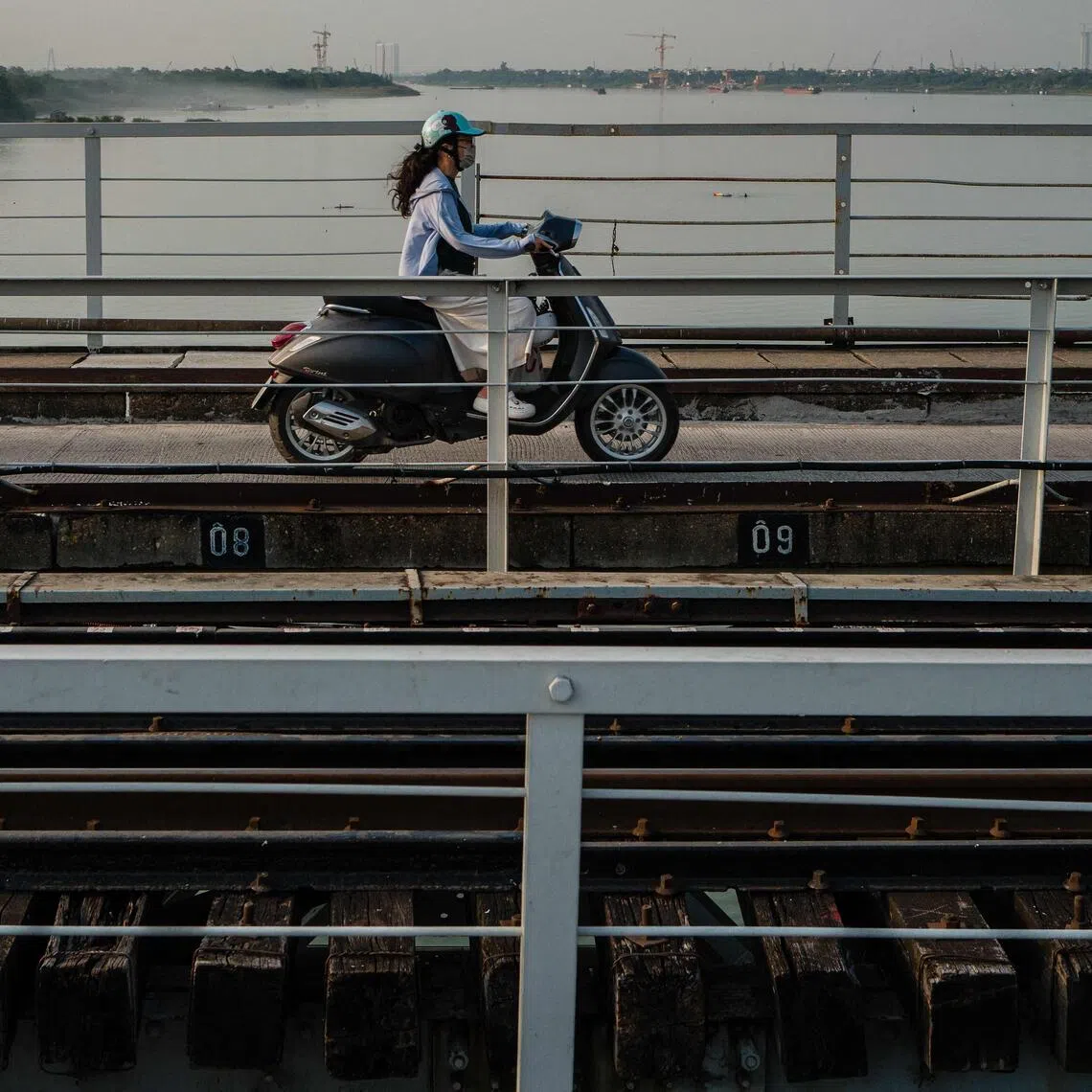 A motorist drives her motorbike on a bridge that runs over the Red River in Hanoi on Oct 23.