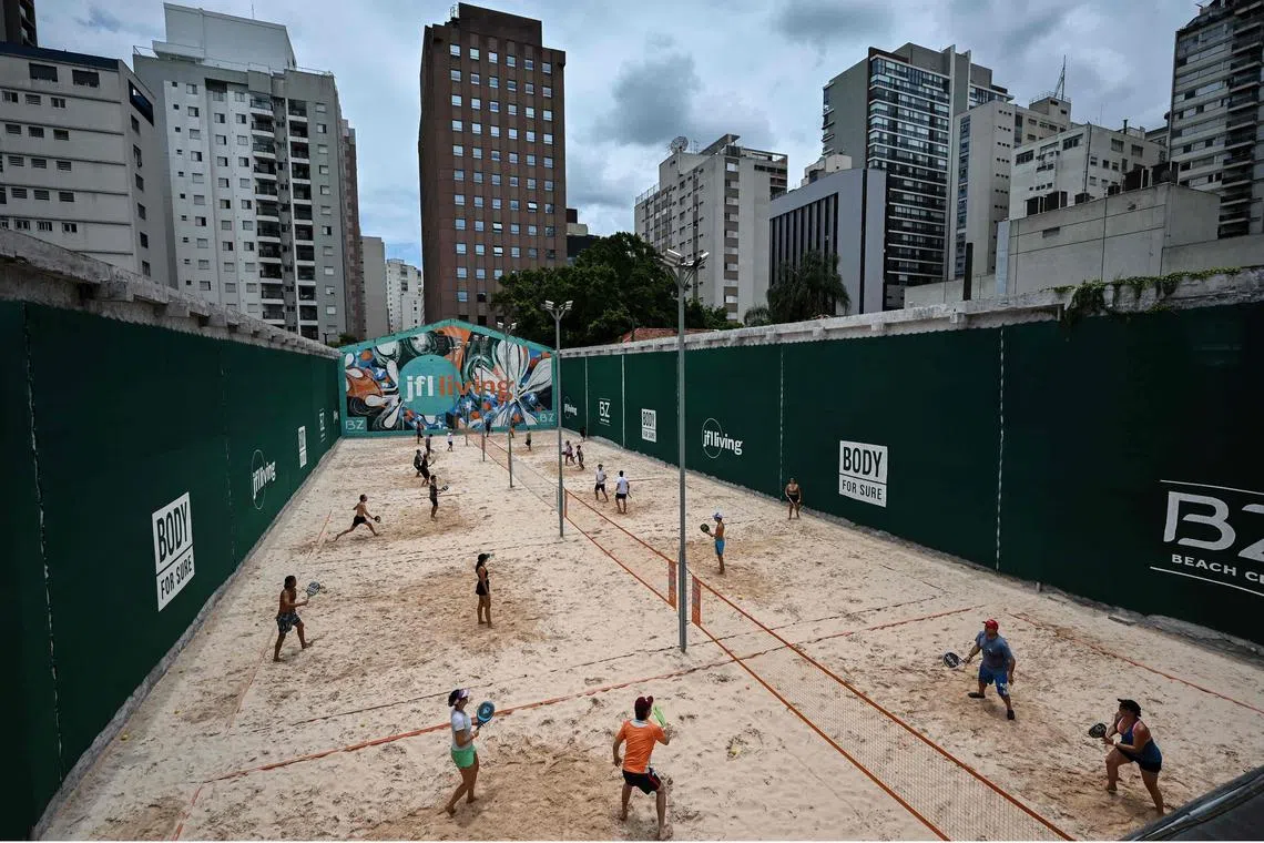 People play beach tennis at a club in Sao Paulo, Brazil, on January 22, 2023. The boom of the beach tennis in Latin America's largest metropolis which lacks beaches has opened up an alternative for Paulistanos, mostly from the middle and upper classes, to put their feet on the sand amid their routine. 