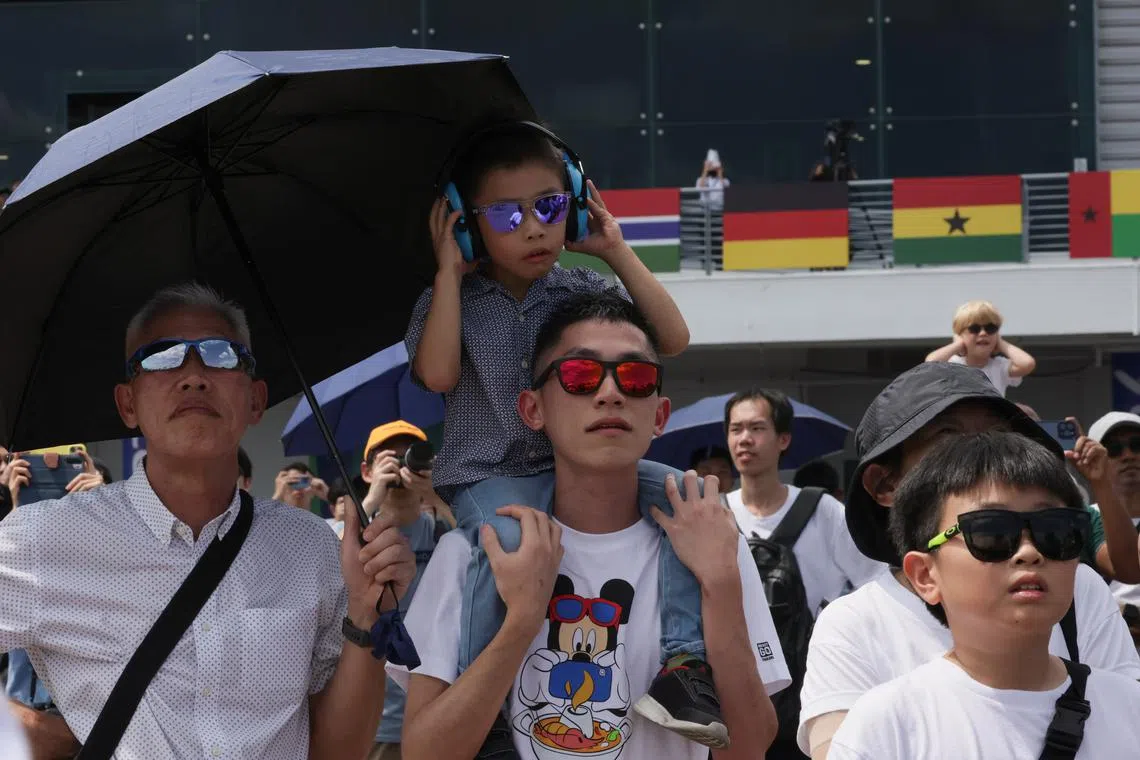 A sitting on his father's shoulders for a better view as they watch the aerial display at the Singapore Airshow at Changi Exhibition Centre, February 24, 2024.