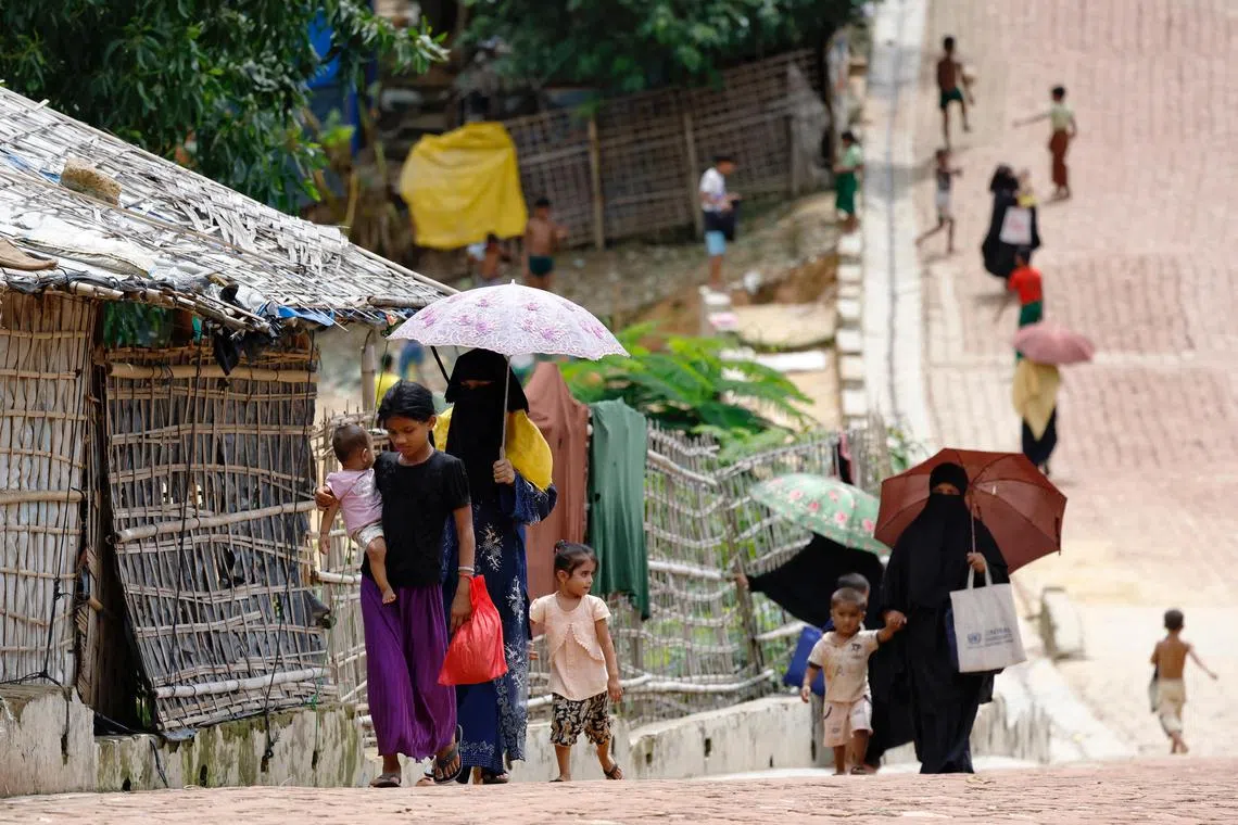 Rohingya refugees walk along the road at the Kutupalang refugee camp in Cox's Bazar, Bangladesh, on June 26.