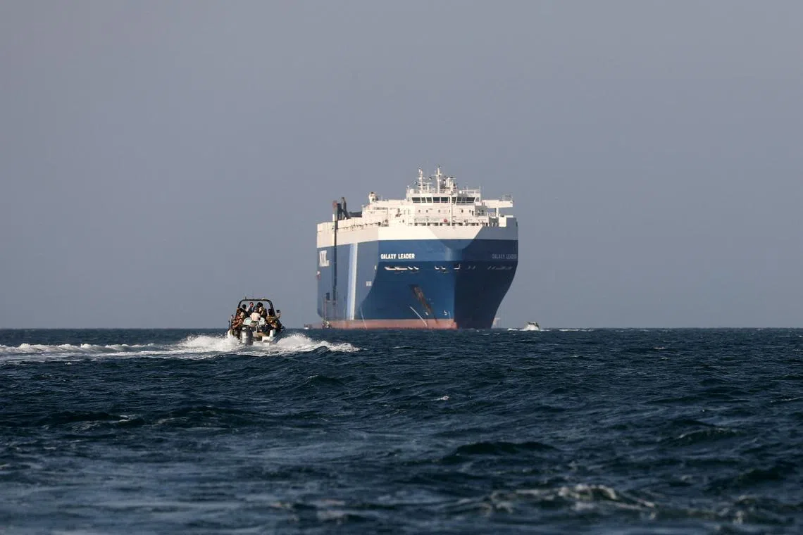 FILE PHOTO: A boat carrying people sails near the Galaxy Leader commercial ship, seized by Yemen's Houthis last month, off the coast of al-Salif, Yemen, December 5, 2023. REUTERS/Khaled Abdullah/File Photo