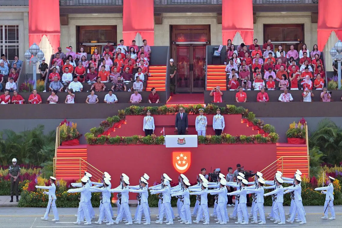 The Republic of Singapore Navy's guard-of-honour contingent marching before President Tharman Shanmugaratnam, as well as ministers and MPs in front of the former City Hall building.