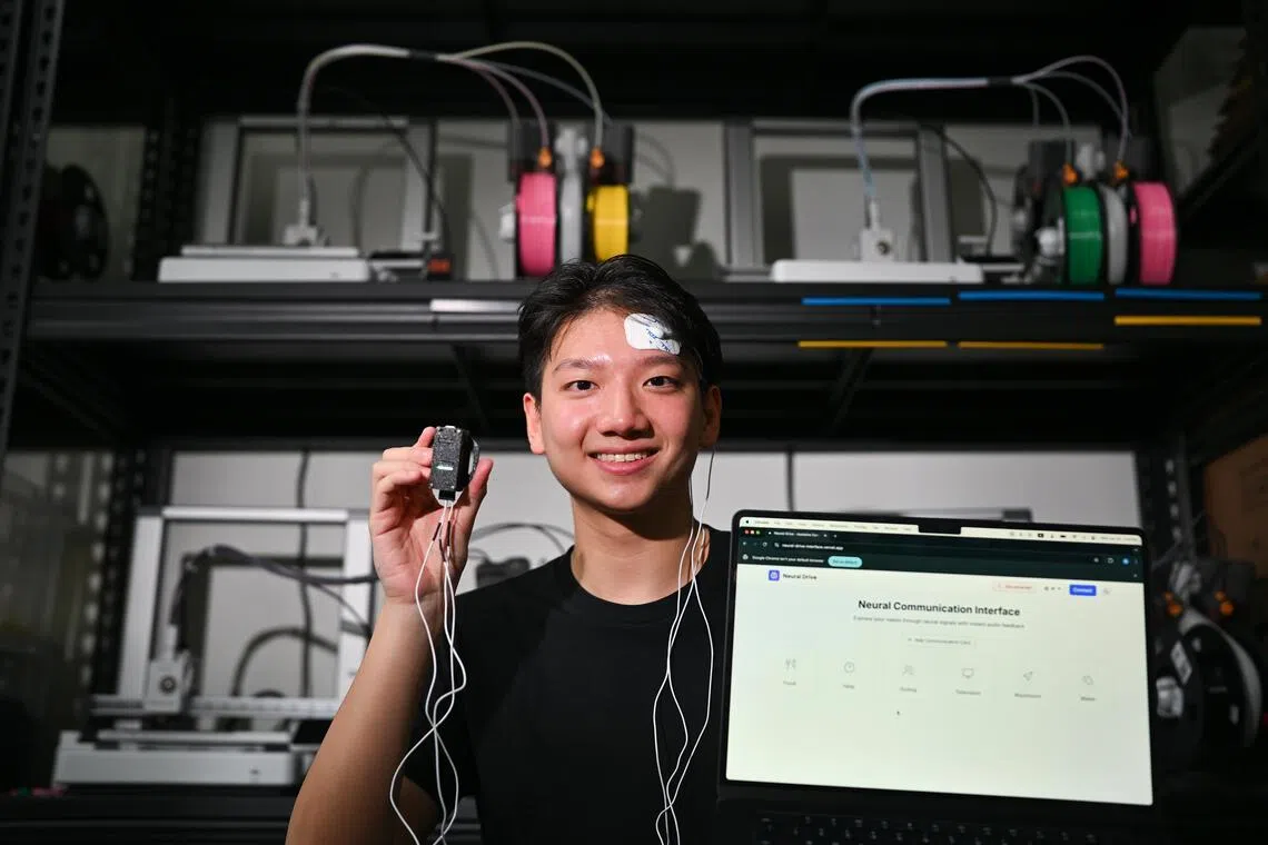 Mr Raymond Ng, 21, Chief AI Officer of Neural Drive, wearing the electrodes and holding the headset with the laptop showing the interface of Neural Drive.