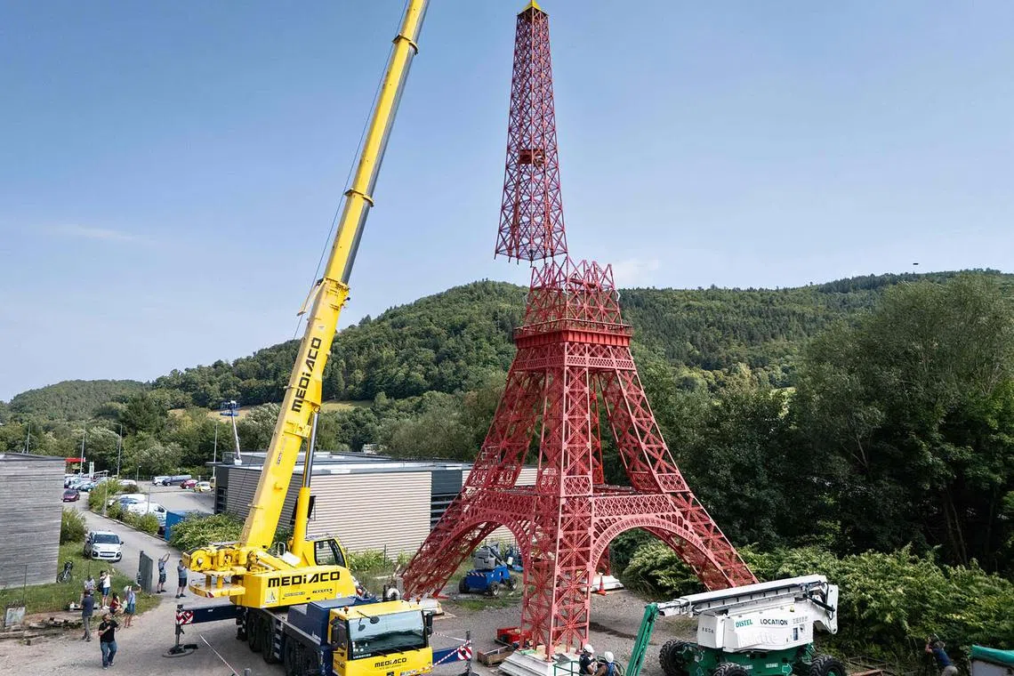 Workers setting up a part of a 31-metre replica of the Eiffel Tower in Sainte-Croix-aux-Mines, eastern France, on Aug 26, 2025. 