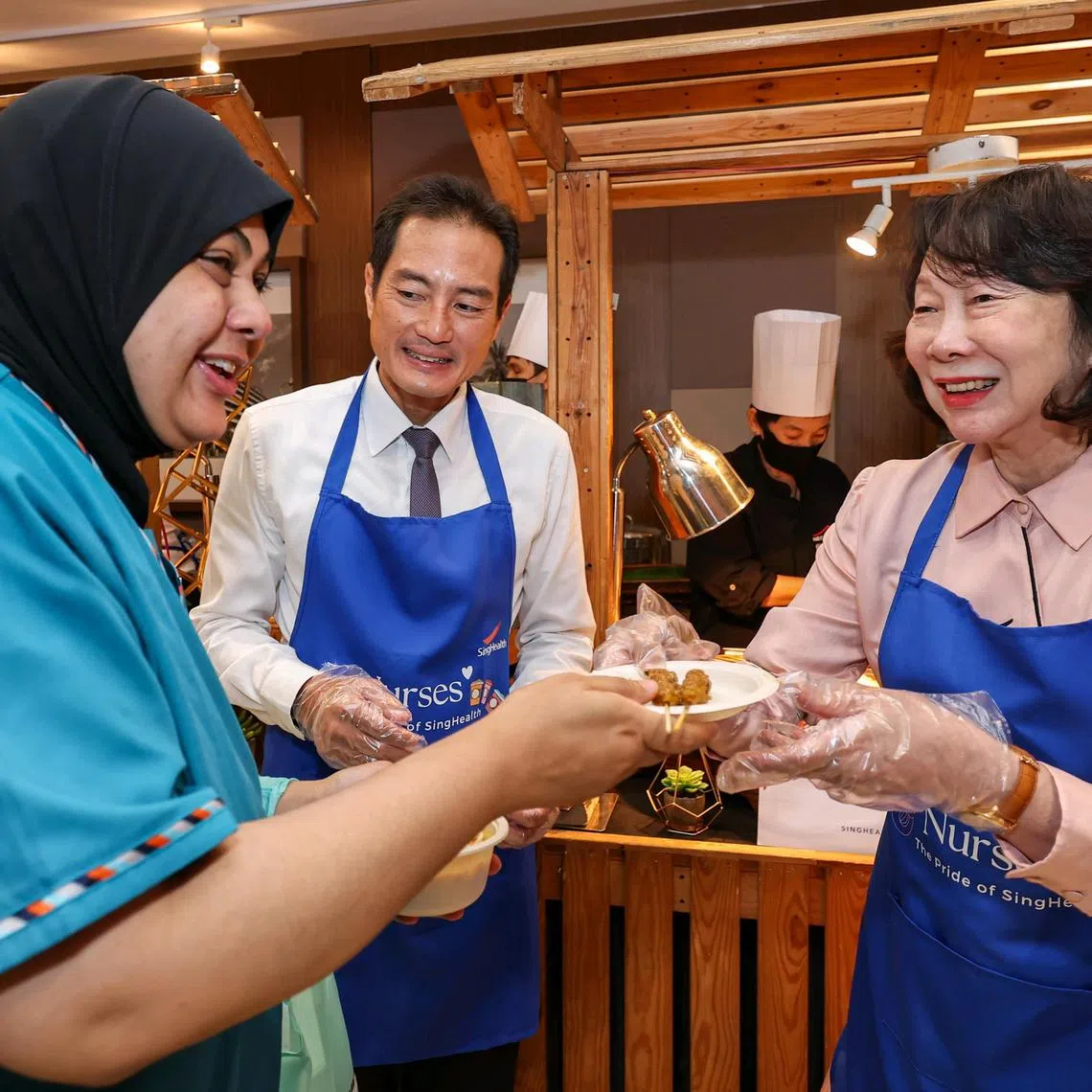 Ms Wee Wei Ling, Wee Foundation director (right), and Senior Minister of State for Health Tan Kiat How serving satay to nurses during the SingHealth Nurses' Day celebrations at The Academia on July 29, 2025.