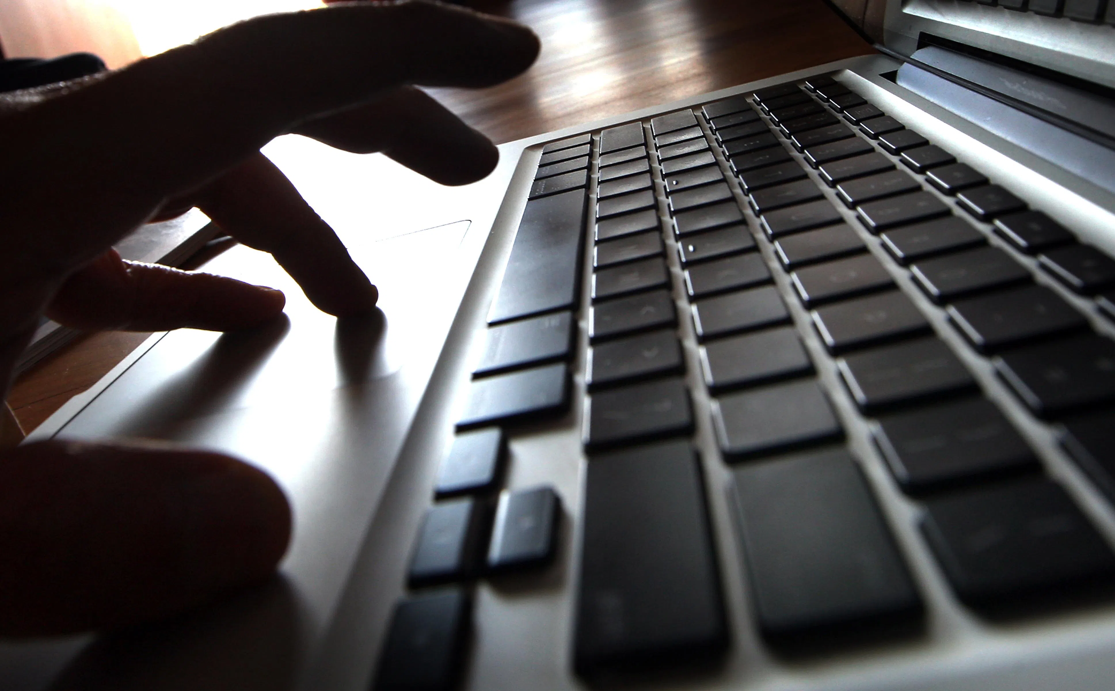 Posed photo of a person with fingers on a laptop to illustrate a story on online bullying (cyber bullying).