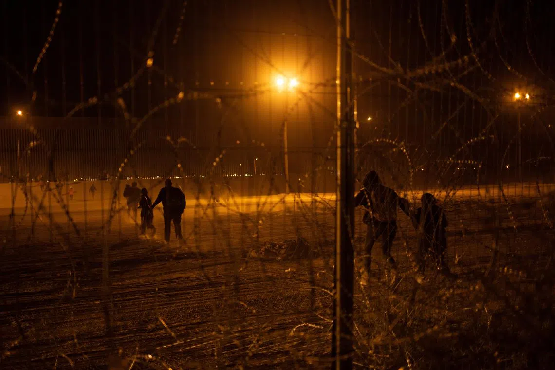 FILE PHOTO: Migrants race towards the border wall after breaching a razor wire fence from the bank of the Rio Grande river after they crossed from Ciudad Juarez, Mexico into El Paso, Texas, U.S., April 3, 2024.  REUTERS/Adrees Latif/File Photo