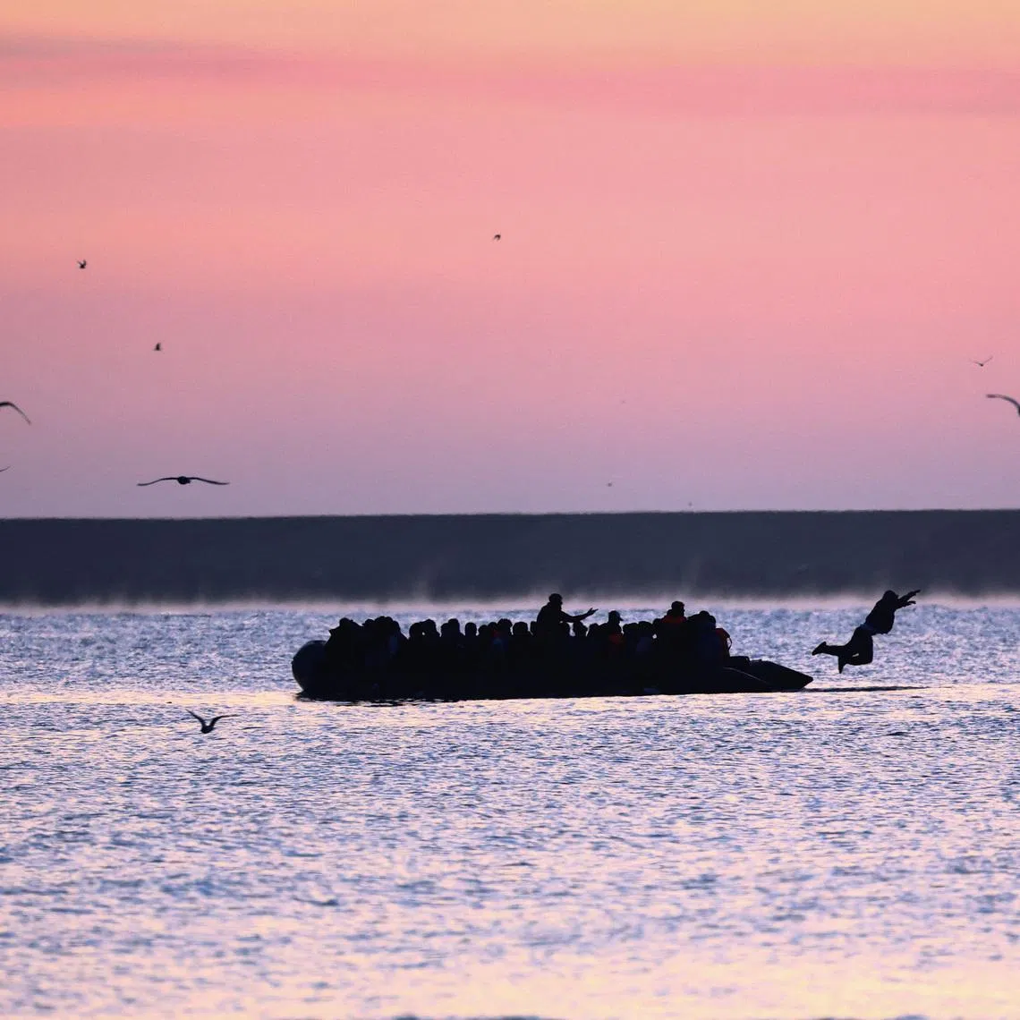 A man jumps into the water from an inflatable dinghy as a group of migrants leave the coast of northern France in an attempt to cross the English Channel to reach Britain as tougher migration controls were announced, from the beach of Petit-Fort-Philippe in Gravelines, near Calais, France, July 17, 2025. REUTERS/Gonzalo Fuentes
