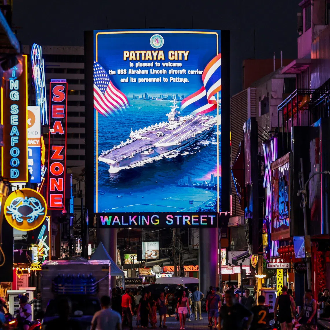 People walk past an LED display welcoming U.S. service personnel from the U.S. Nimitz-class aircraft carrier USS Abraham Lincoln, which is docked at Laem Chabang Port for a rest stop following a long deployment in the Middle East, in Pattaya City, Thailand, September 3, 2026. REUTERS/Chalinee Thirasupa