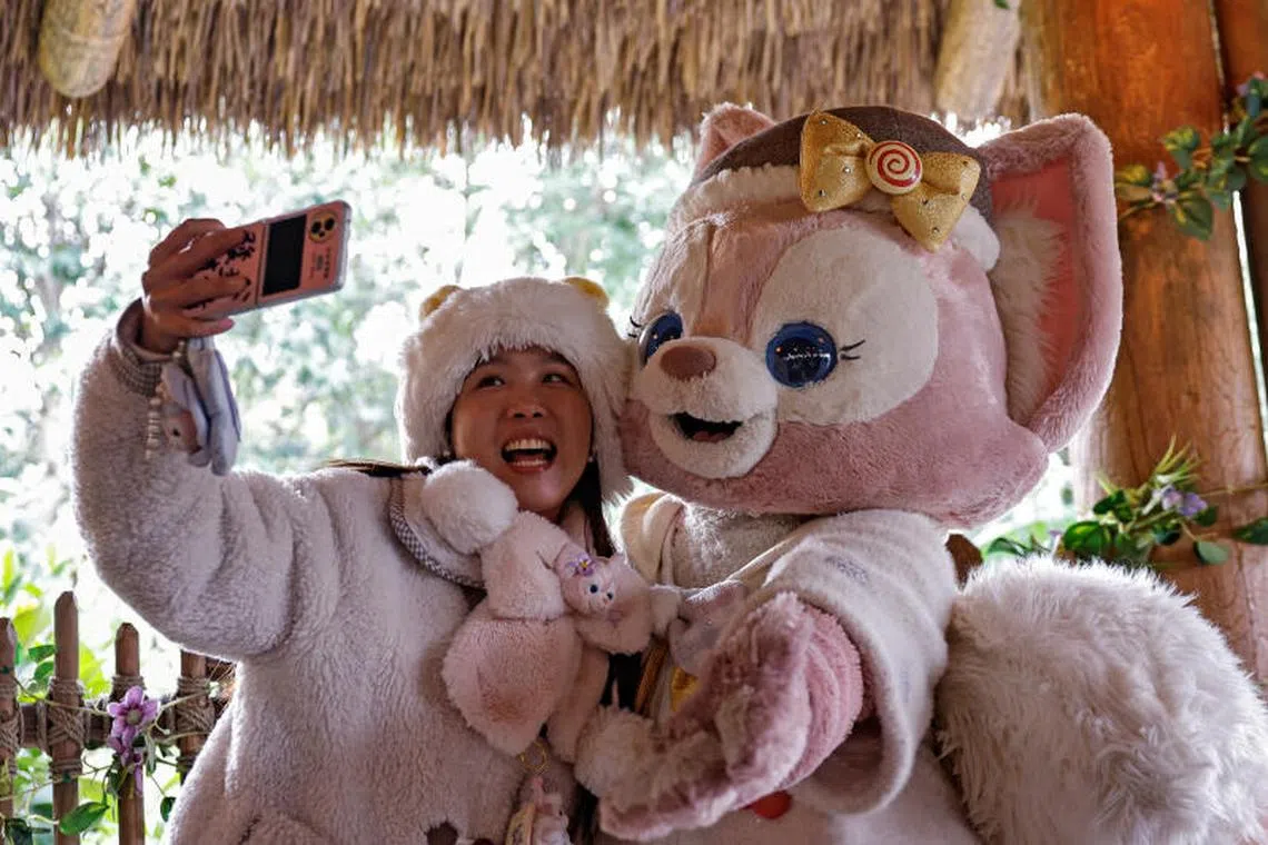 A fan takes a selfie with a performer dressed as the character LinaBell, a pink fox character from the Disney series Duffy and Friends, at Shanghai Disneyland, in China on  Dec 23, 2024. 
