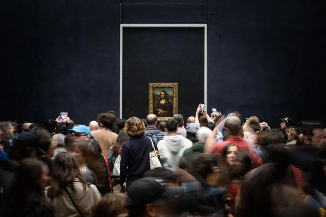 Visitors photograph the Mona Lisa by Italian artist Leonardo Da Vinci on display in a gallery at The Louvre Museum in Paris in 2023. 