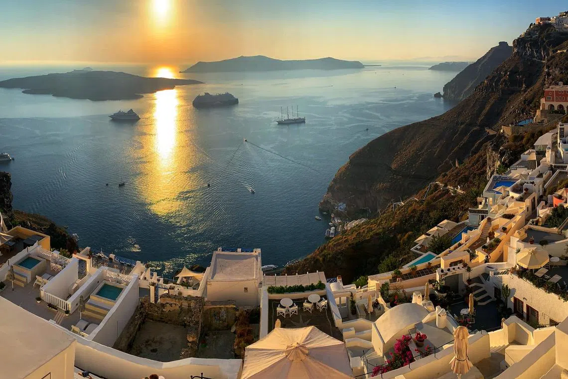 Sunset from Santorini’s Fira village in Greece. The fastest ferry to Santorini from Athens takes more than four hours, versus one hour by chopper.
