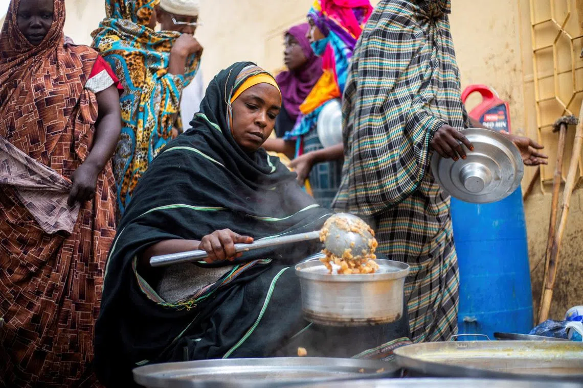 FILE PHOTO: A Sudanese woman from a community kitchen run by local volunteers distributes meals for people who are affected by conflict and extreme hunger and are out of reach of international aid efforts, in Omdurman, Sudan, August 22, 2024. REUTERS/Mazin Alrasheed/File Photo