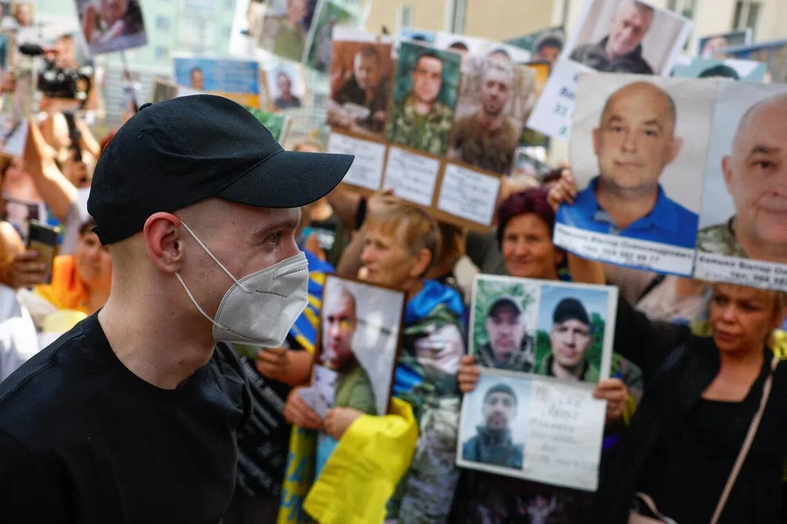 A freed Ukrainian prisoner of war walking past the relatives of other prisoners who are still in captivity, in August 2025..