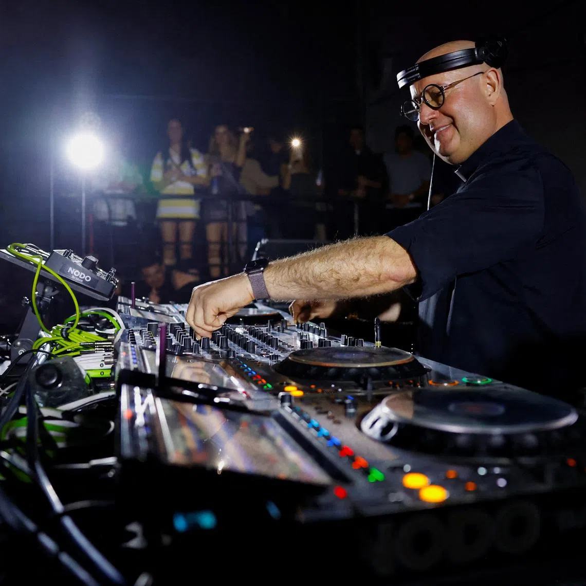 Portuguese Catholic priest Father Guilherme Peixoto, who has gained international recognition as a DJ, particularly among young people, performs on a turntable before a packed dance floor at a venue filled with revelers, in Monterrey, Mexico, December 14, 2025. REUTERS/Daniel Becerril