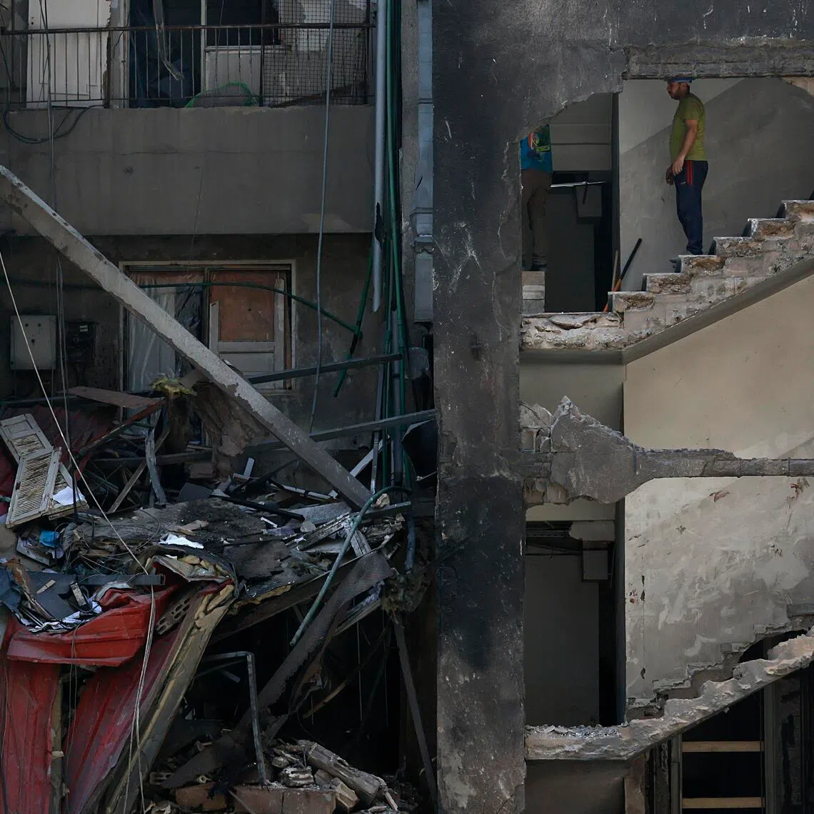 Workers stand inside a partially destroyed building in Corniche el Mazraa, in Beirut, Lebanon, on April 13, 2026.