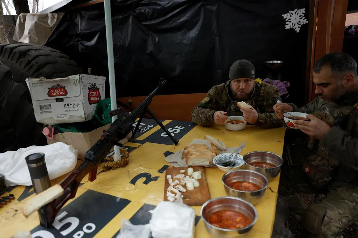 Ukrainian servicemen eat a meal of borscht and bread near the front line in Bakhmut, Ukraine, on Dec 24, 2022.